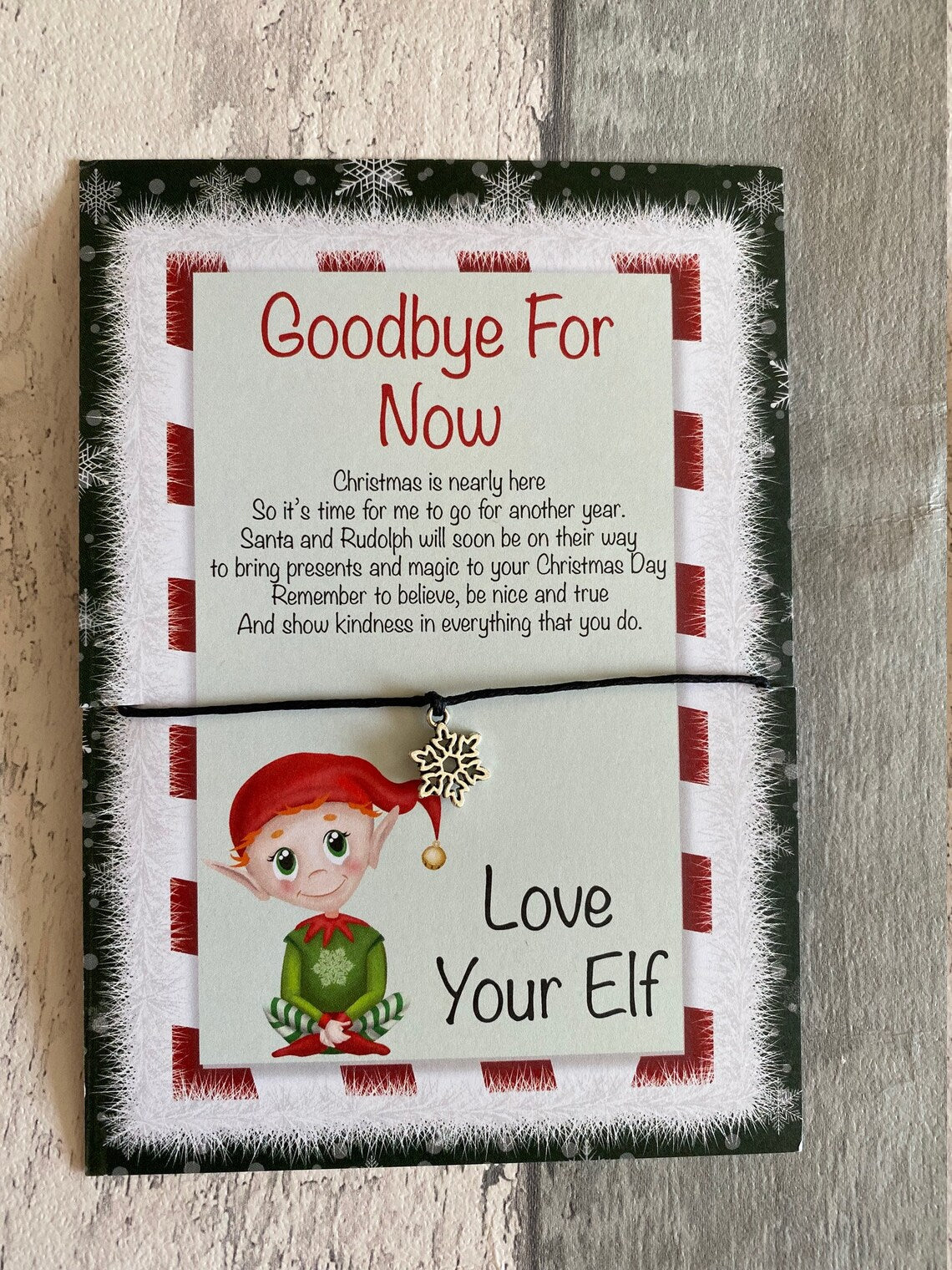 Goodbye for Now wish bracelet with text and an elf illustration on a wooden surface
