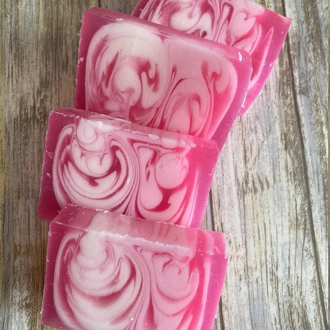 Rose Pink and white swirled soap bars on a wooden surface