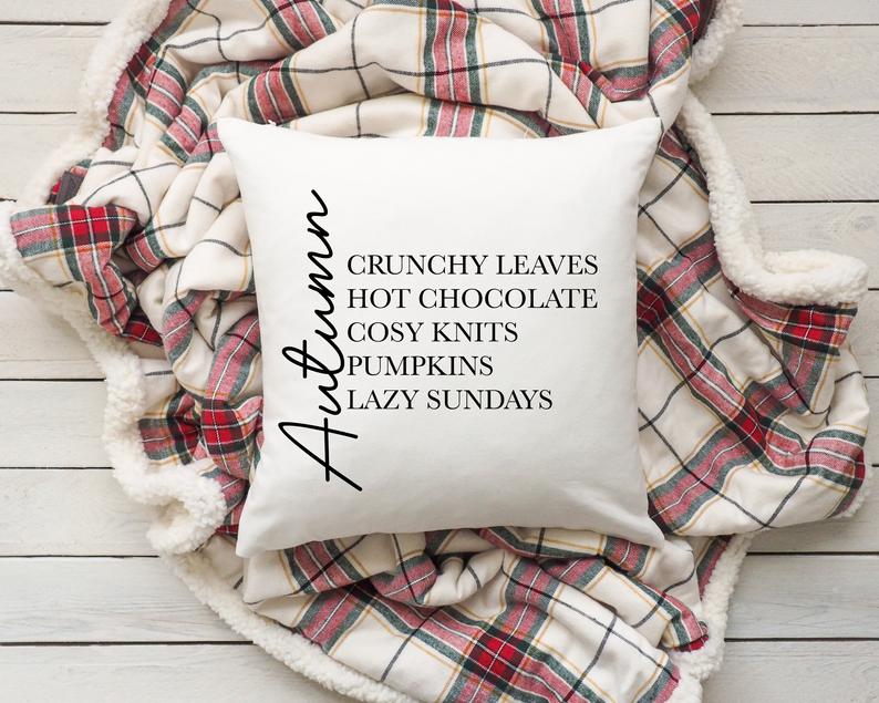 Decorative pillow with autumn-themed text on a plaid blanket