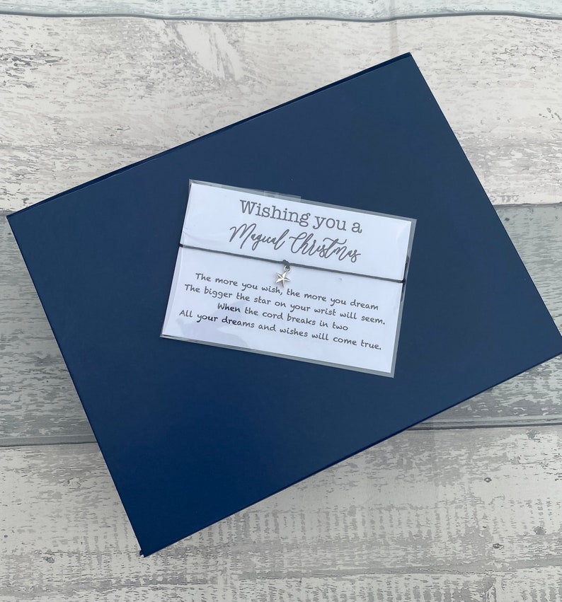 Navy blue card with a white card inside containing text and a small charm on a wooden surface.