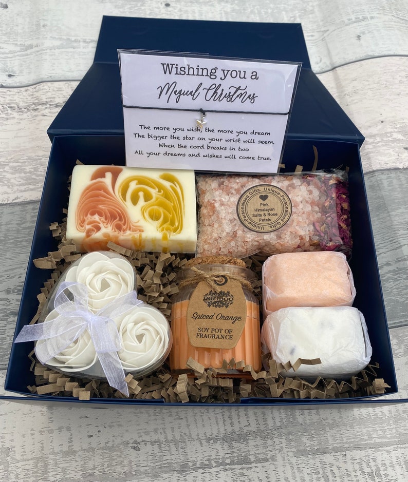 Gift box with soaps, candles, and a card on a wooden surface