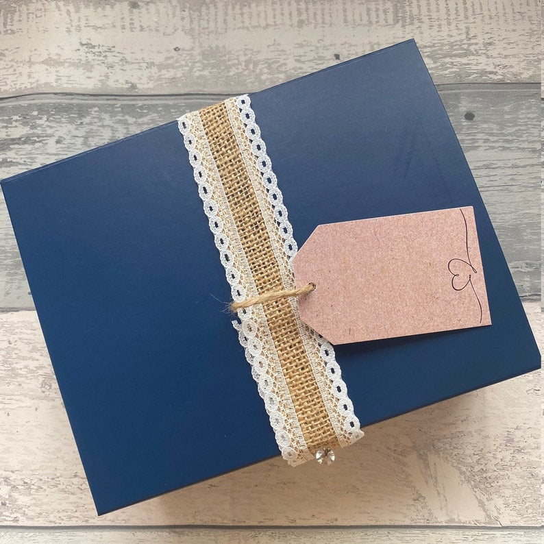 Blue box with lace ribbon and gift tag on a wooden surface