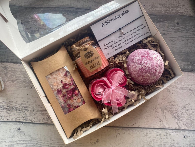 Gift box with bath bomb, soap, and flowers on a wooden surface
