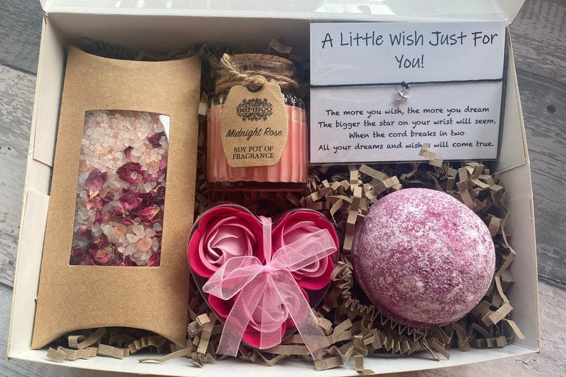 Gift set with bath bomb, candle, and bath salts in a box on a wooden surface