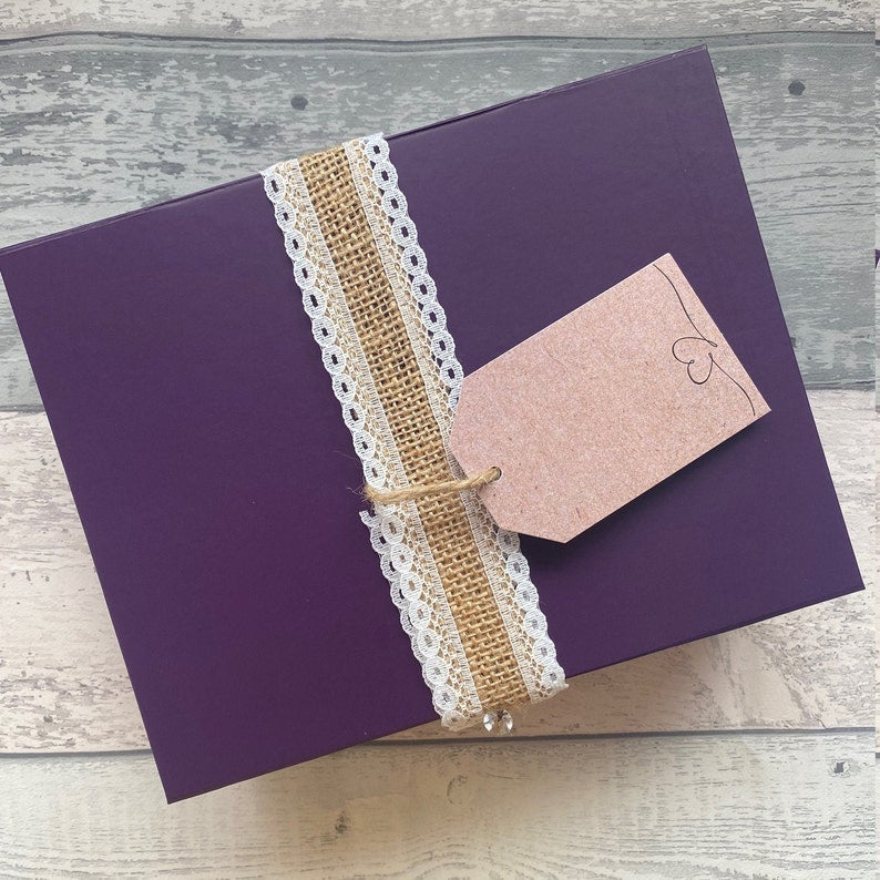 Purple gift box with decorative ribbon and card on a wooden surface