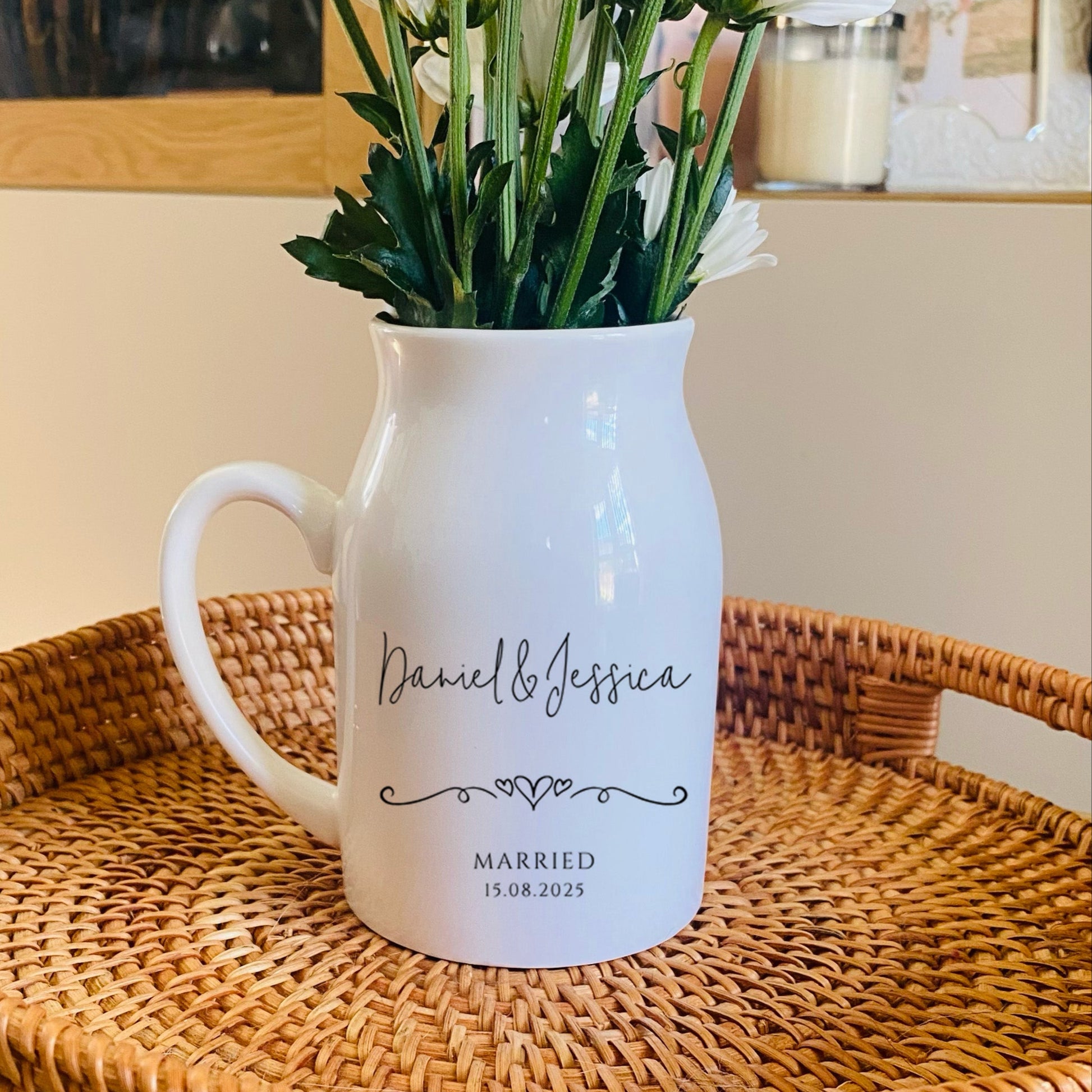 Personalised Wedding Vase. White pitcher with floral arrangement on a woven tray in a home setting