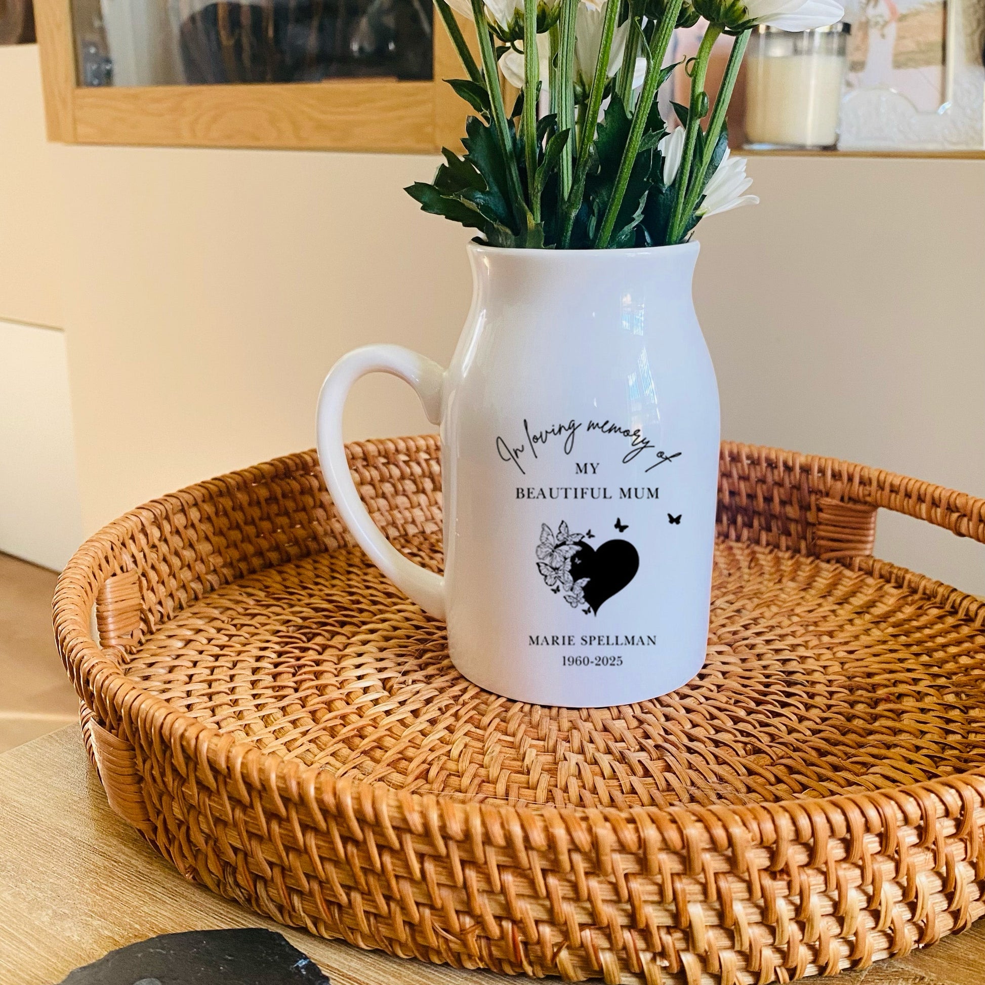 White memorial vase pitcher with floral arrangement on a woven tray