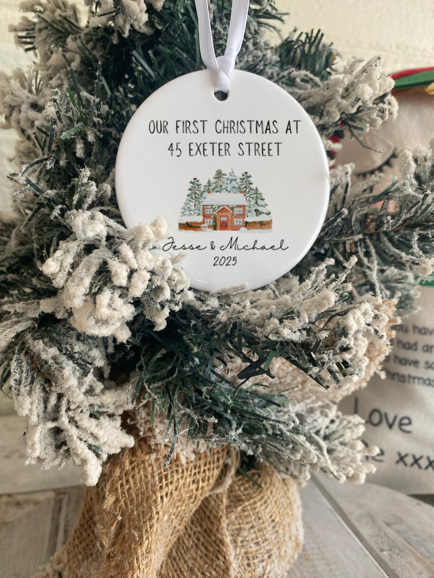 Decorative ornament with a snowy village design on a wreath, featuring text 'Our First Christmas at 45 Exeter Street'.