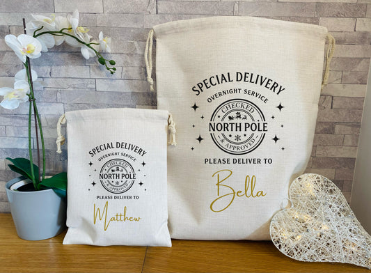Two white drawstring bags with 'Special Delivery' text and personalized names on a wooden surface.