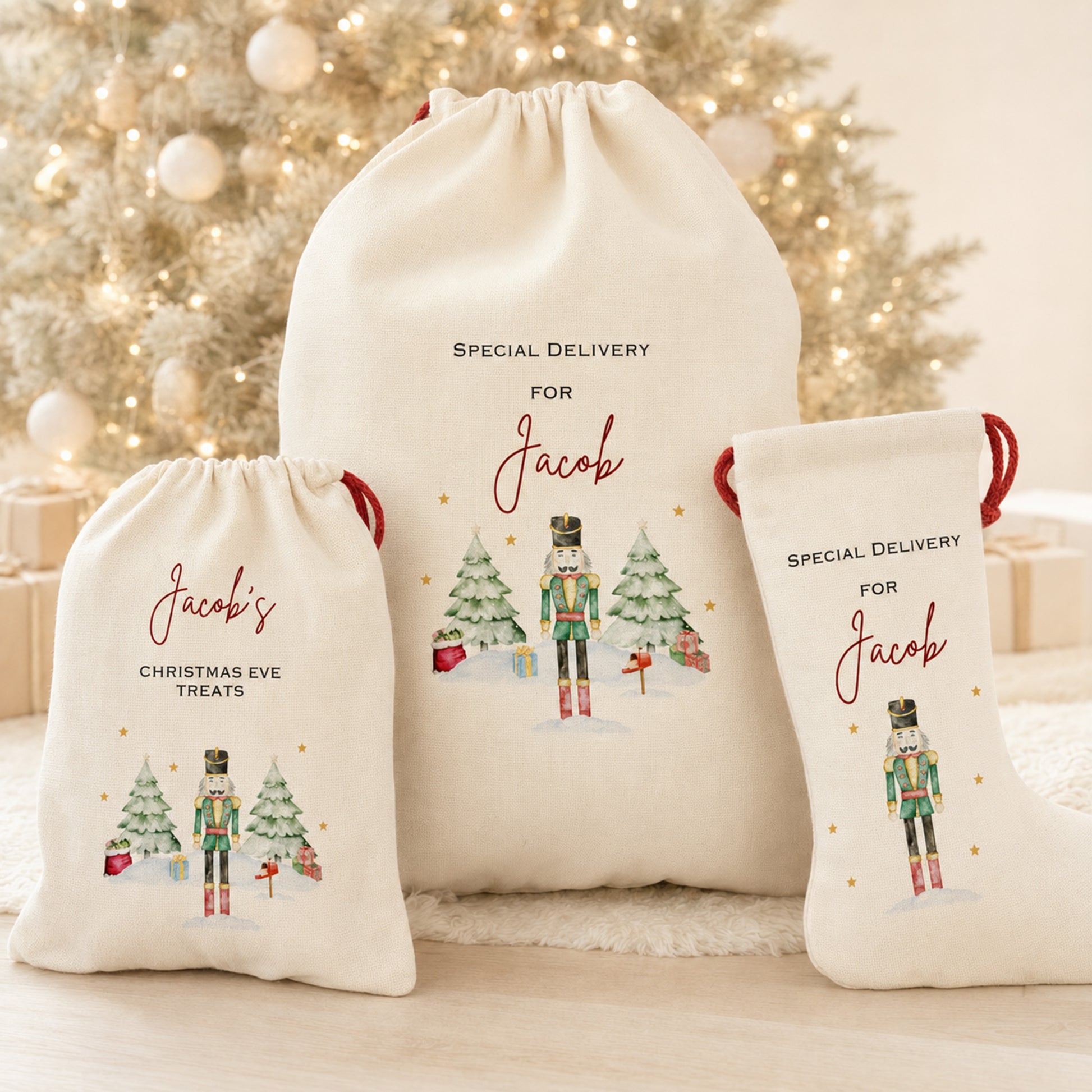 Three personalized cream-colored fabric drawstring gift bags with red handles, featuring nutcracker illustrations and text including 'SPECIAL DELIVERY FOR Jacob' and 'Jacob's CHRISTMAS EVE TREATS', arranged in front of a softly blurred decorated Christmas tree.