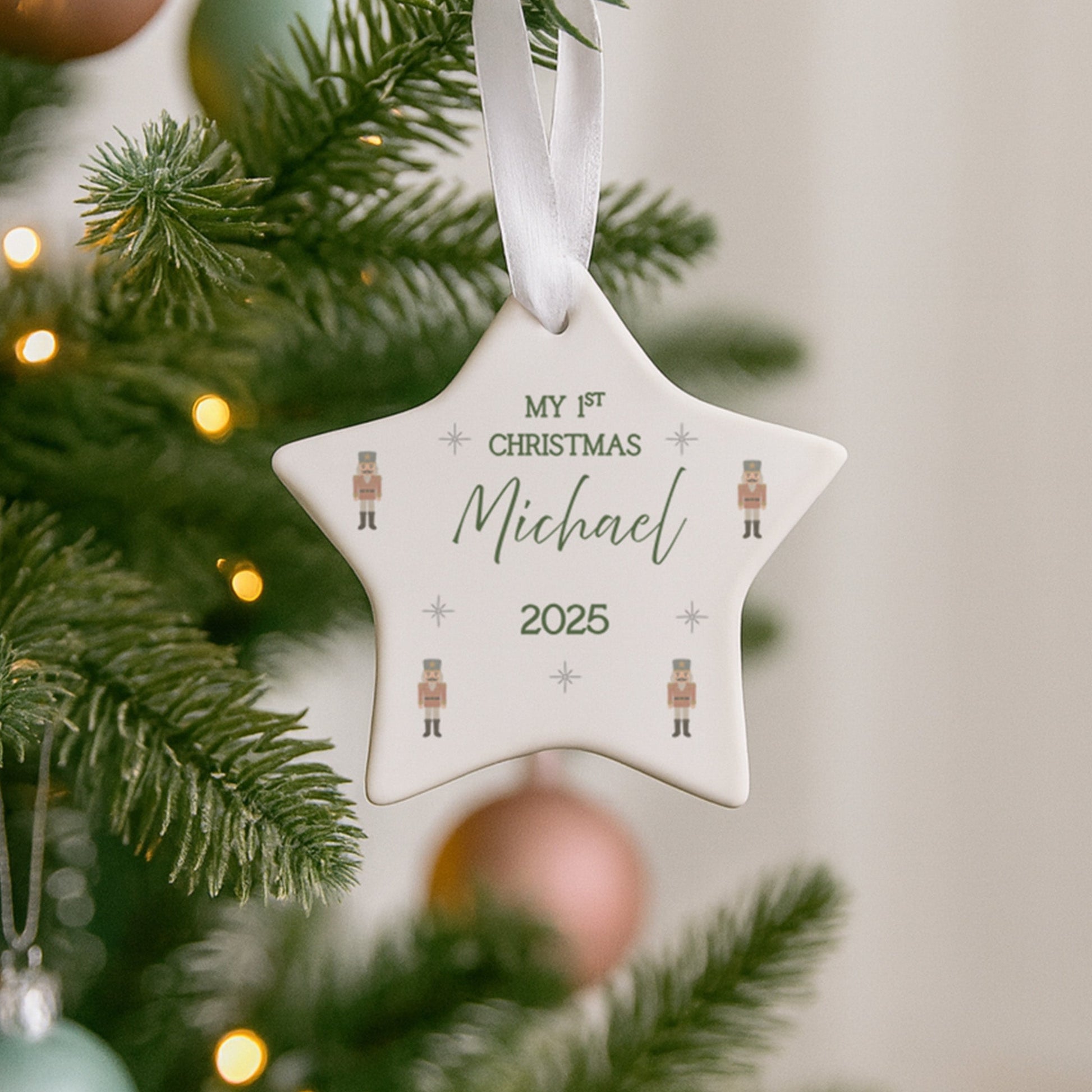 Star-shaped ornament with 'My 1st Christmas Michael 2025' text hanging on a decorated Christmas tree.