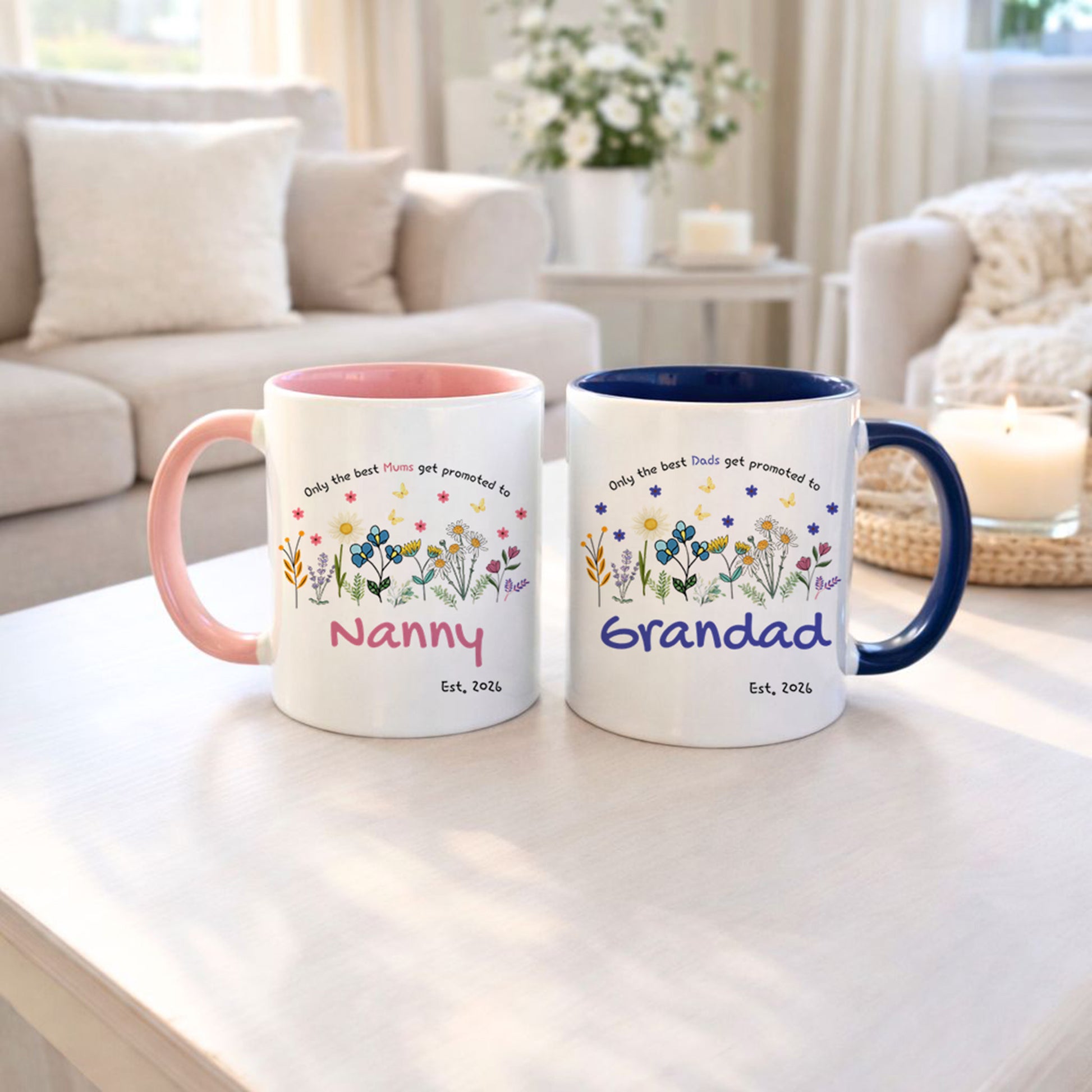 Two mugs with floral designs and text on a table in a living room setting.