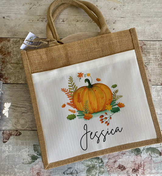 Tote bag with pumpkin design and 'Jessica' text on a wooden surface