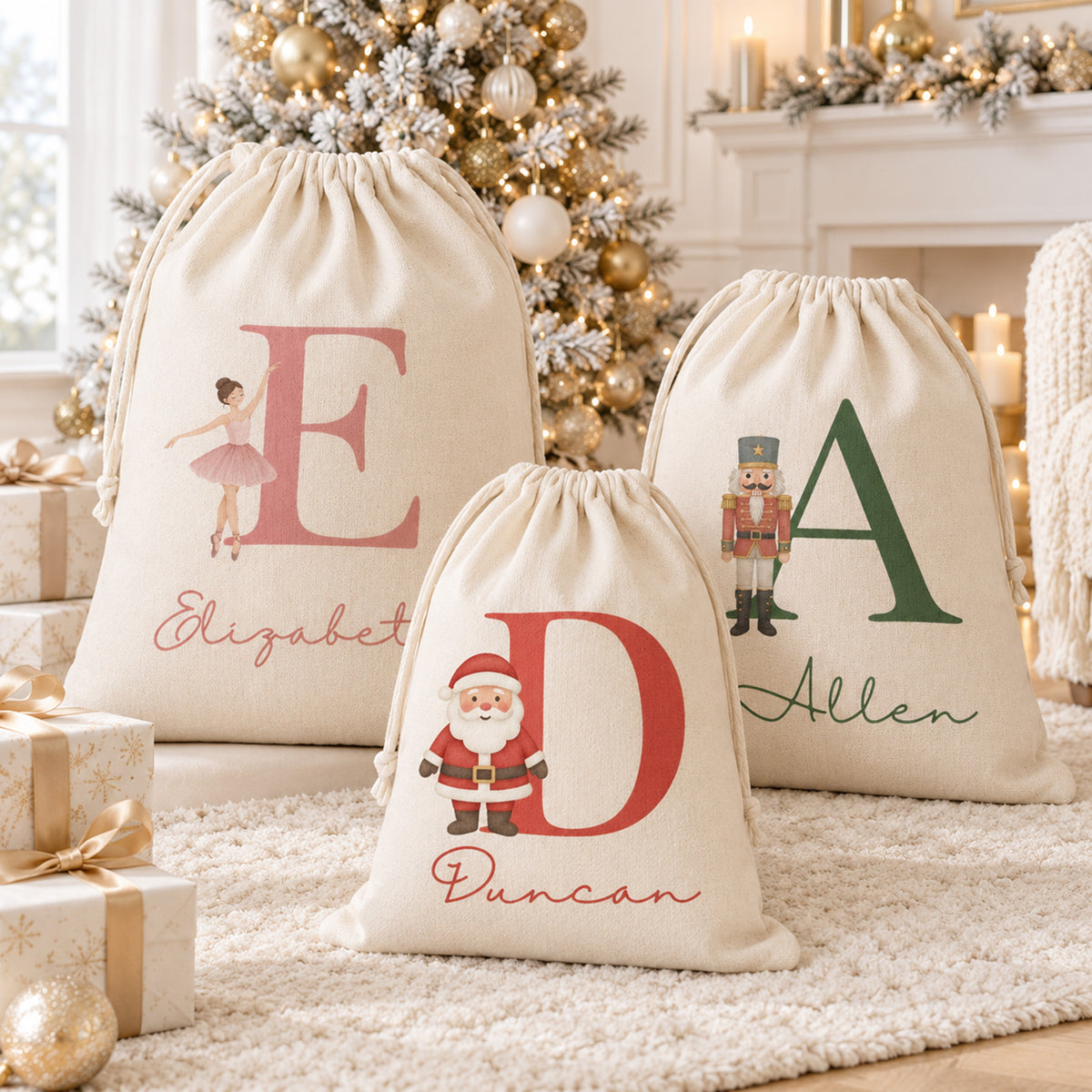 Three personalized Christmas drawstring gift bags displayed on a white rug in front of a decorated Christmas tree and fireplace. The bags are made of a textured cream linen fabric and feature large personalized letters and names with holiday-themed illustrations: a ballerina with the name Elizabeth, a Santa Claus figure with the name Duncan, and a nutcracker with the name Allen.