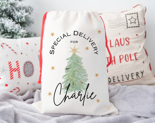 Personalised Christmas delivery sack with festive tree design and Charlie's name in black script on cream linen drawstring bag