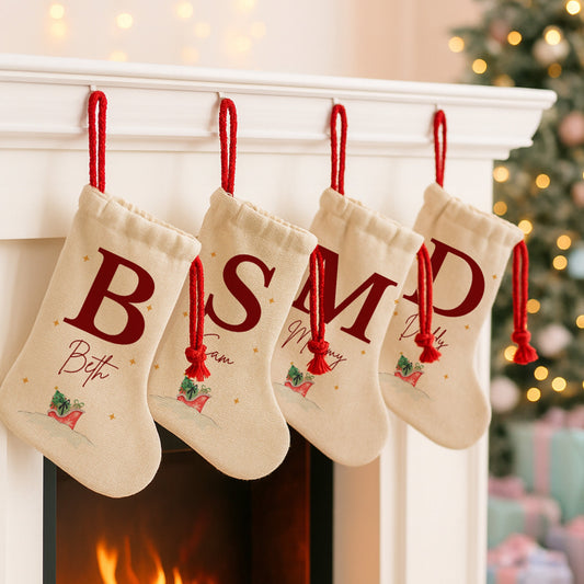 Four Christmas stockings with monogrammed letters hanging on a fireplace mantle.