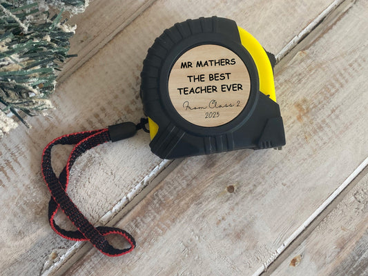 Tape measure with personalized message on a wooden surface