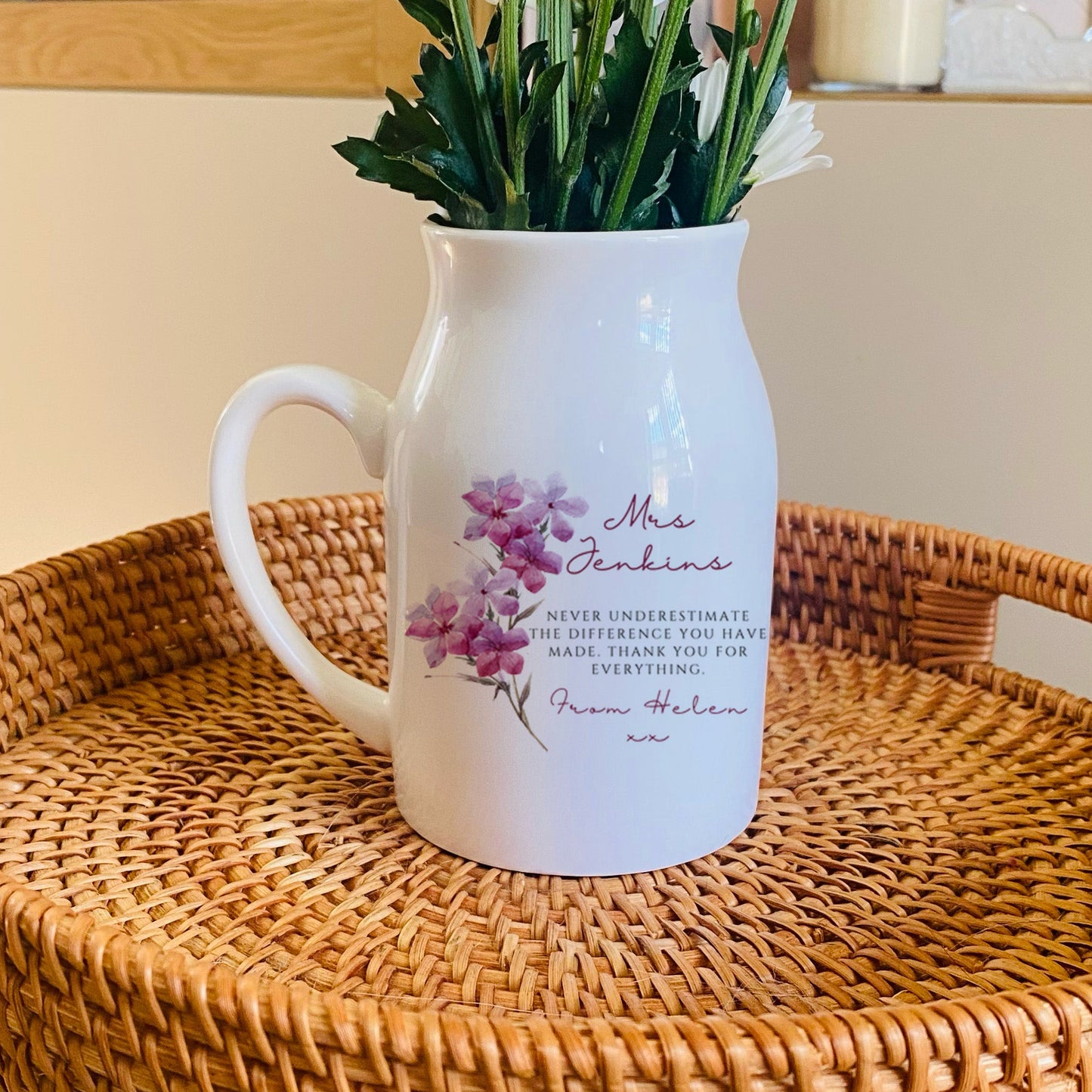 White personalised Teacher pitcher vase with floral design on a woven tray with a blurred background