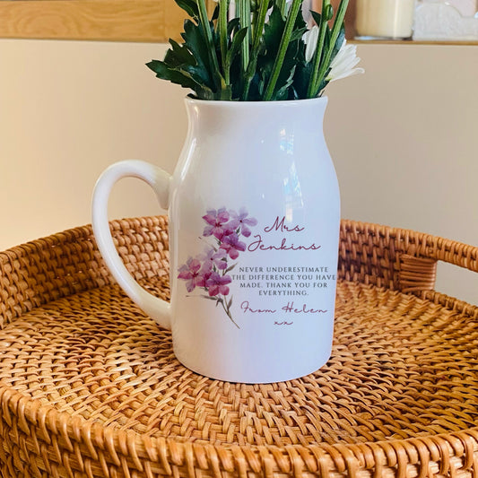 White personalised Teacher pitcher vase with floral design on a woven tray with a blurred background