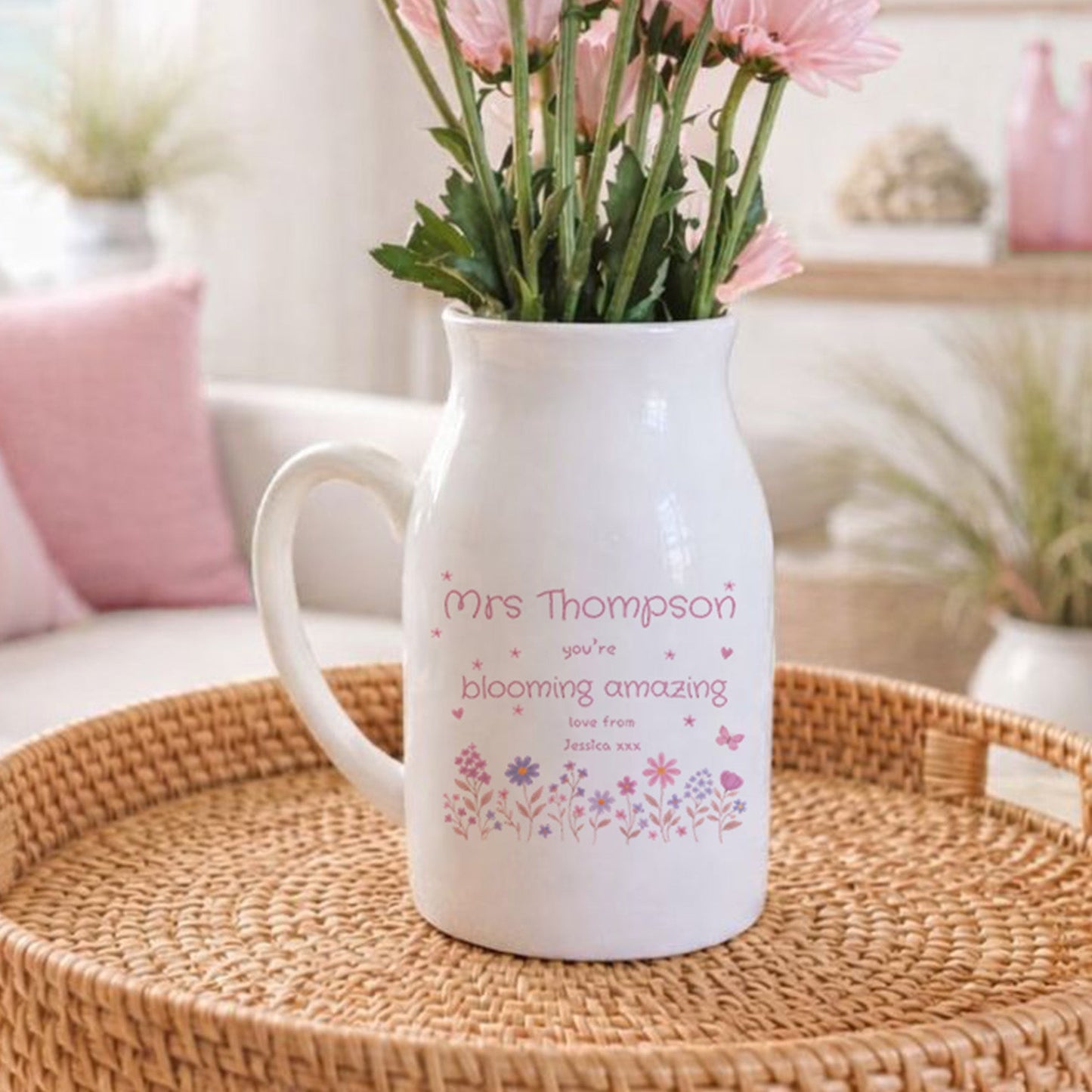 White pitcher with pink flowers on a woven tray in a living room setting