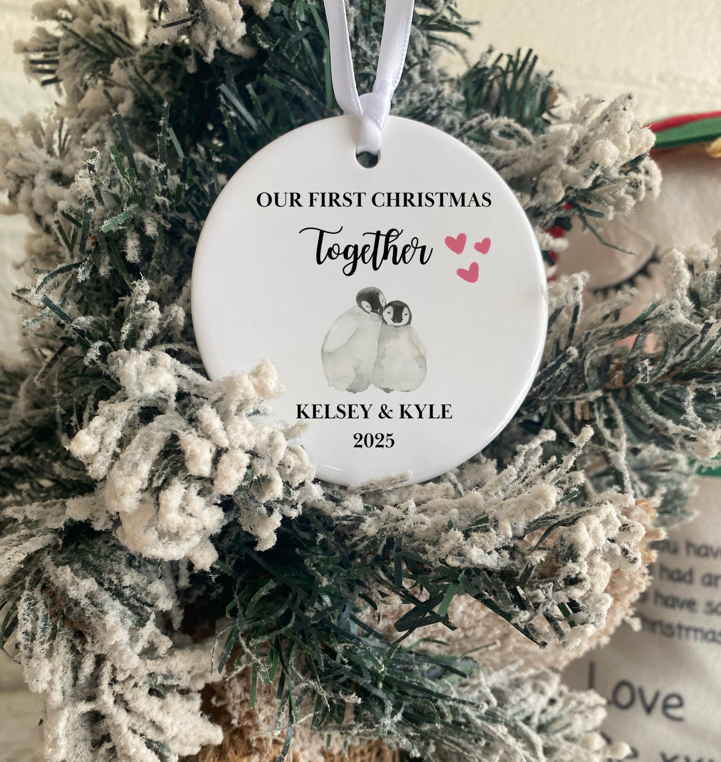 Personalised First Christmas Together ornament with penguins and text on a decorated tree.