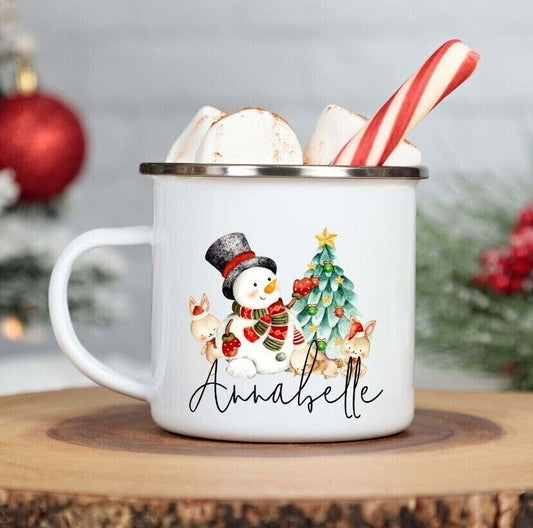 White mug with a snowman design, filled with hot chocolate and marshmallows, on a wooden surface.