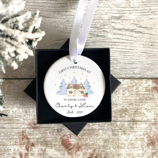 Personalised Christmas ornament with a First Christmas in new home house design in a black box on a wooden surface. 